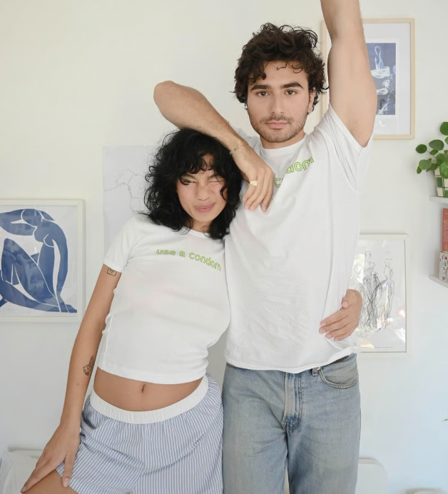 Two people posing indoors, one holding a box labeled 'Jems'.