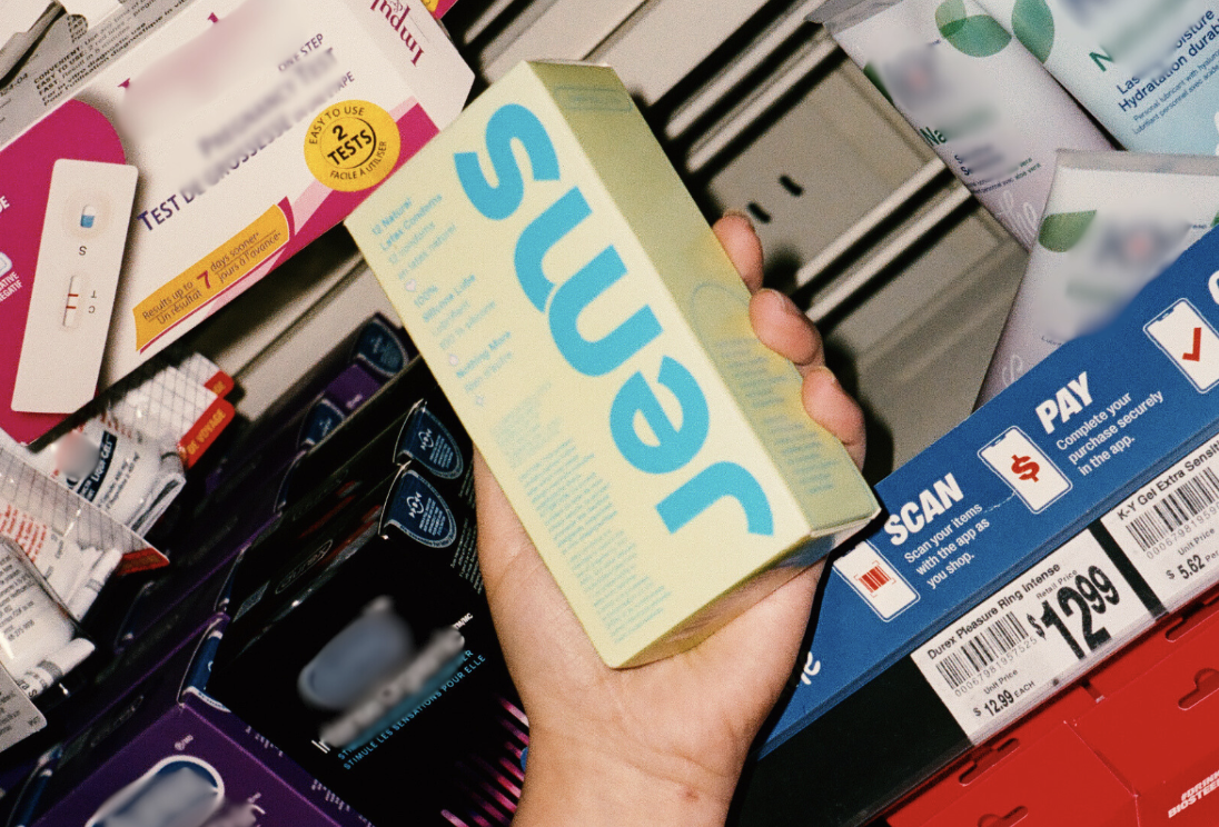 Two people posing indoors, one holding a box labeled 'Jems'.