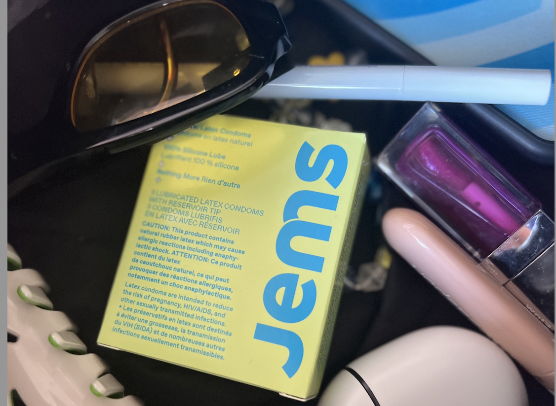Box of condoms, sunglasses, cosmetic items, and a vape device.