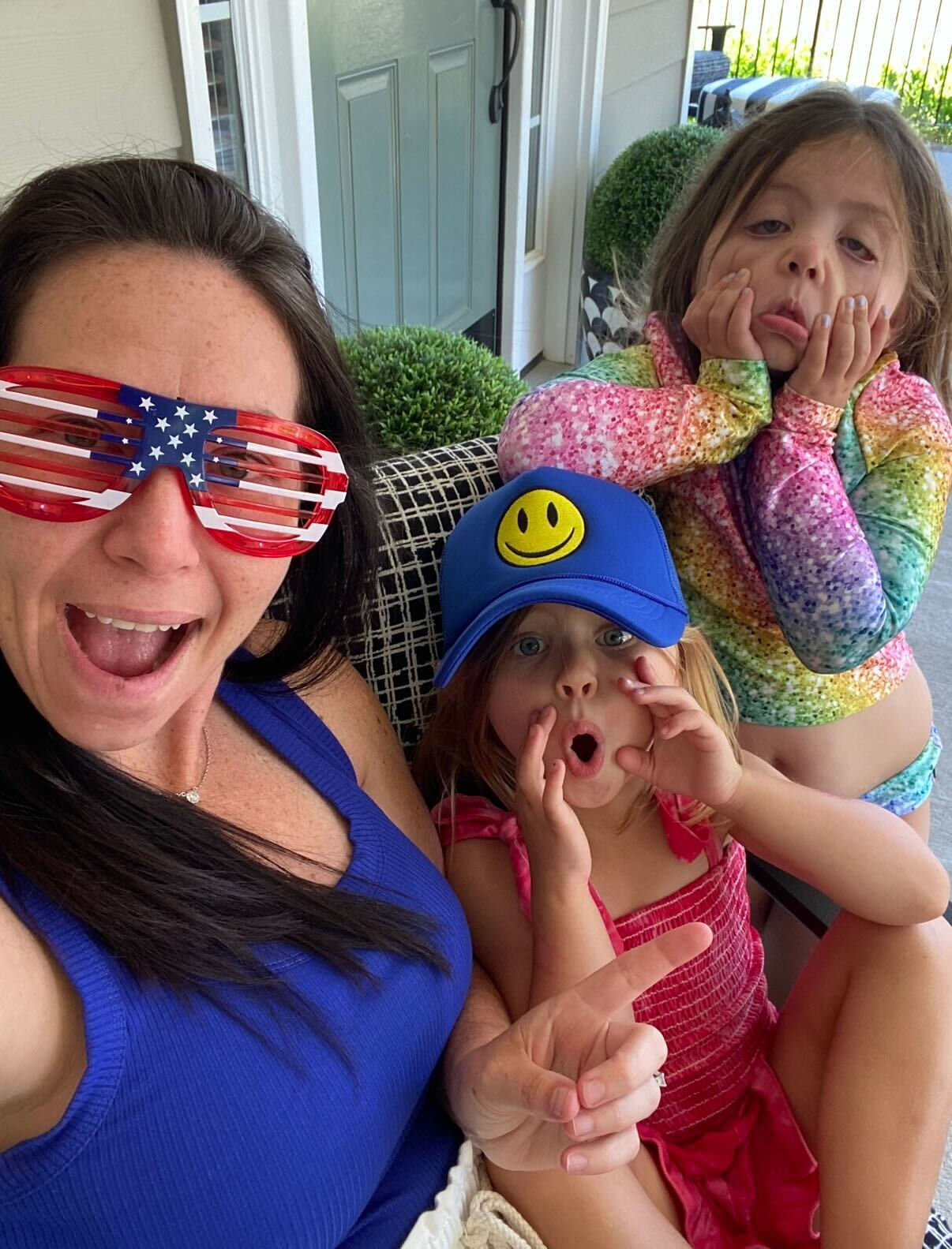 Three people making funny faces, one wearing American flag sunglasses.