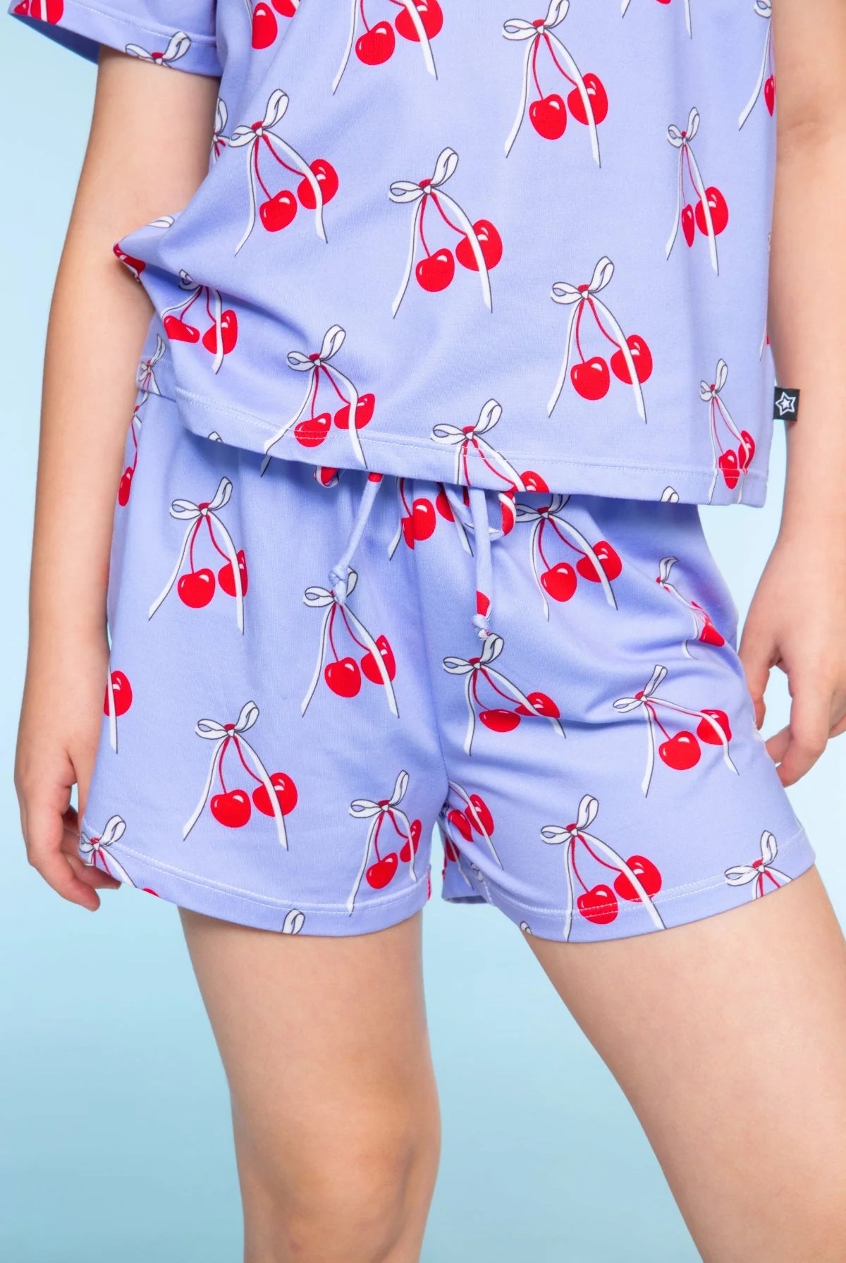 Person wearing purple pajamas with red cherry pattern.