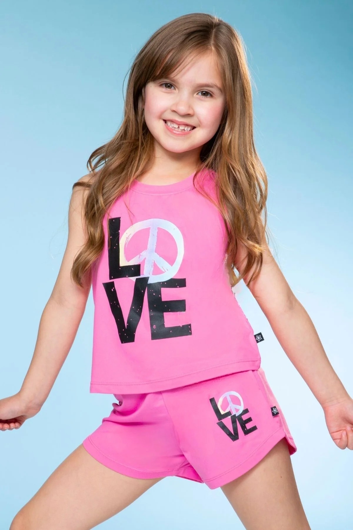 Smiling child in pink outfit with 'LOVE' text and peace symbol.
