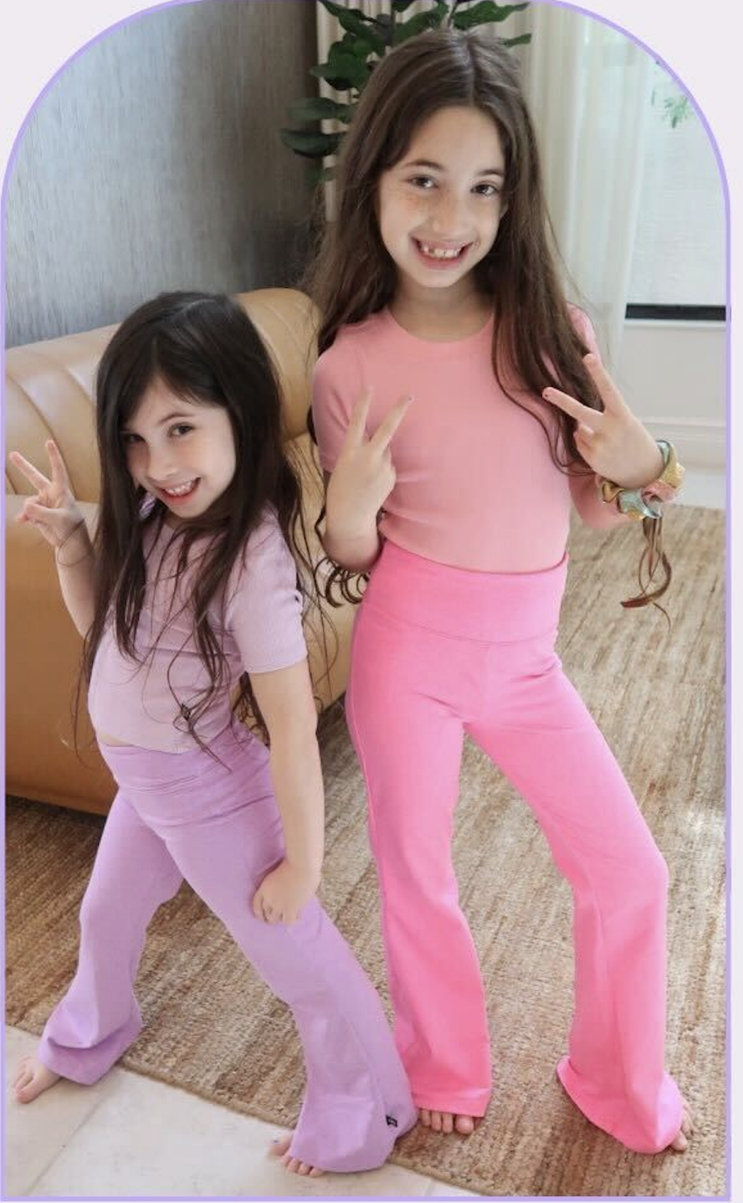 Two girls posing with peace signs, wearing pink and purple outfits.