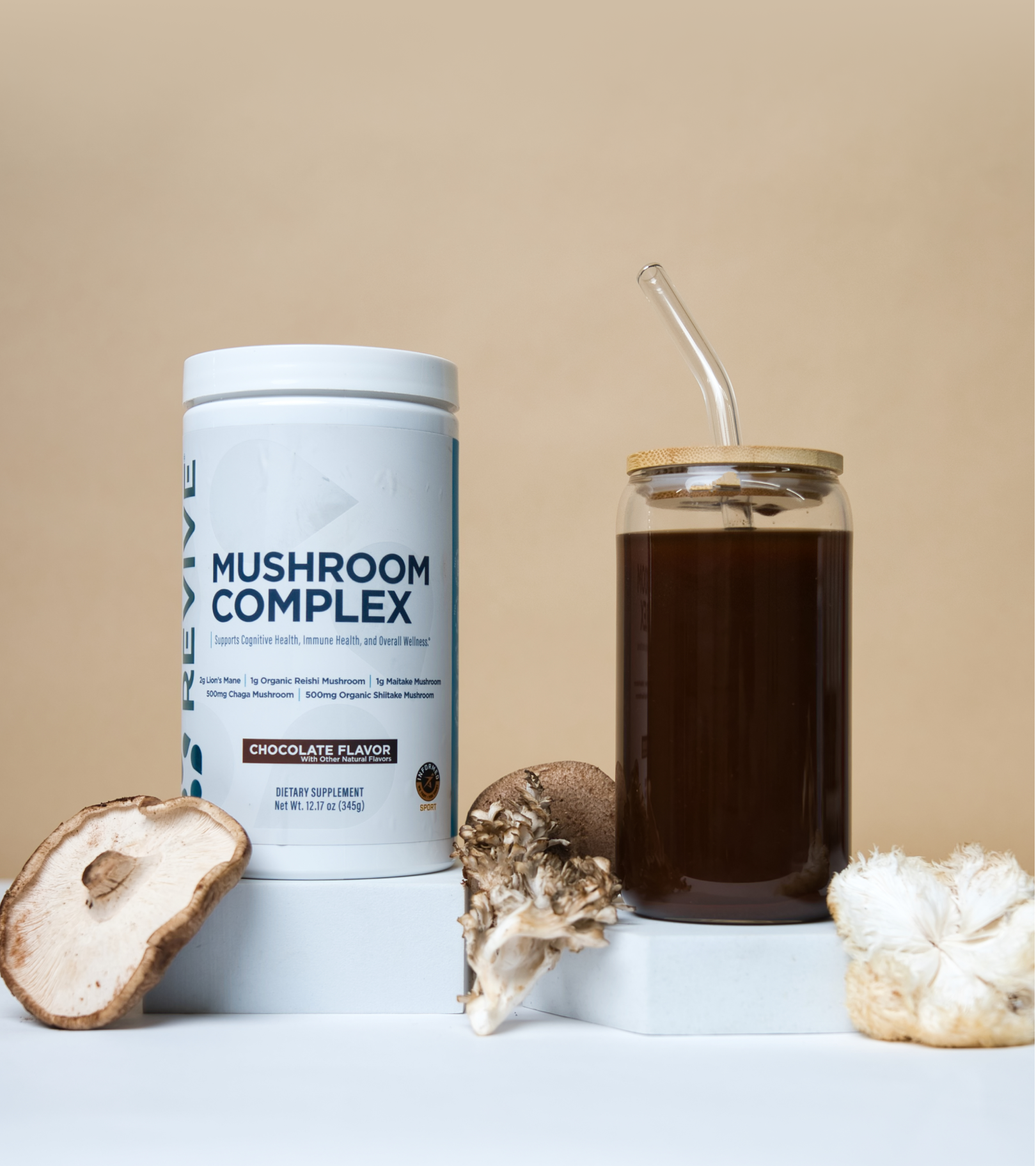 Mushroom supplement container and glass with straw, surrounded by various mushrooms.
