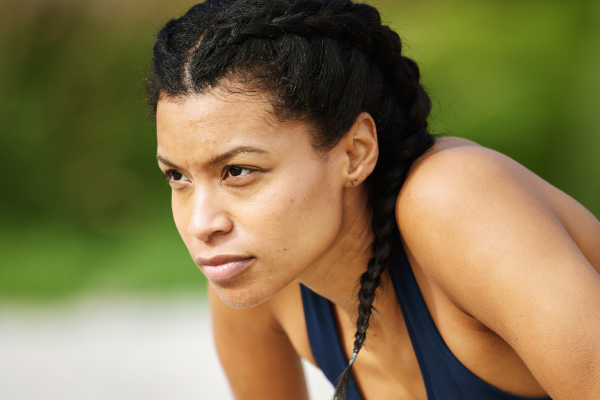 Woman with braided hair in athletic pose outdoors.