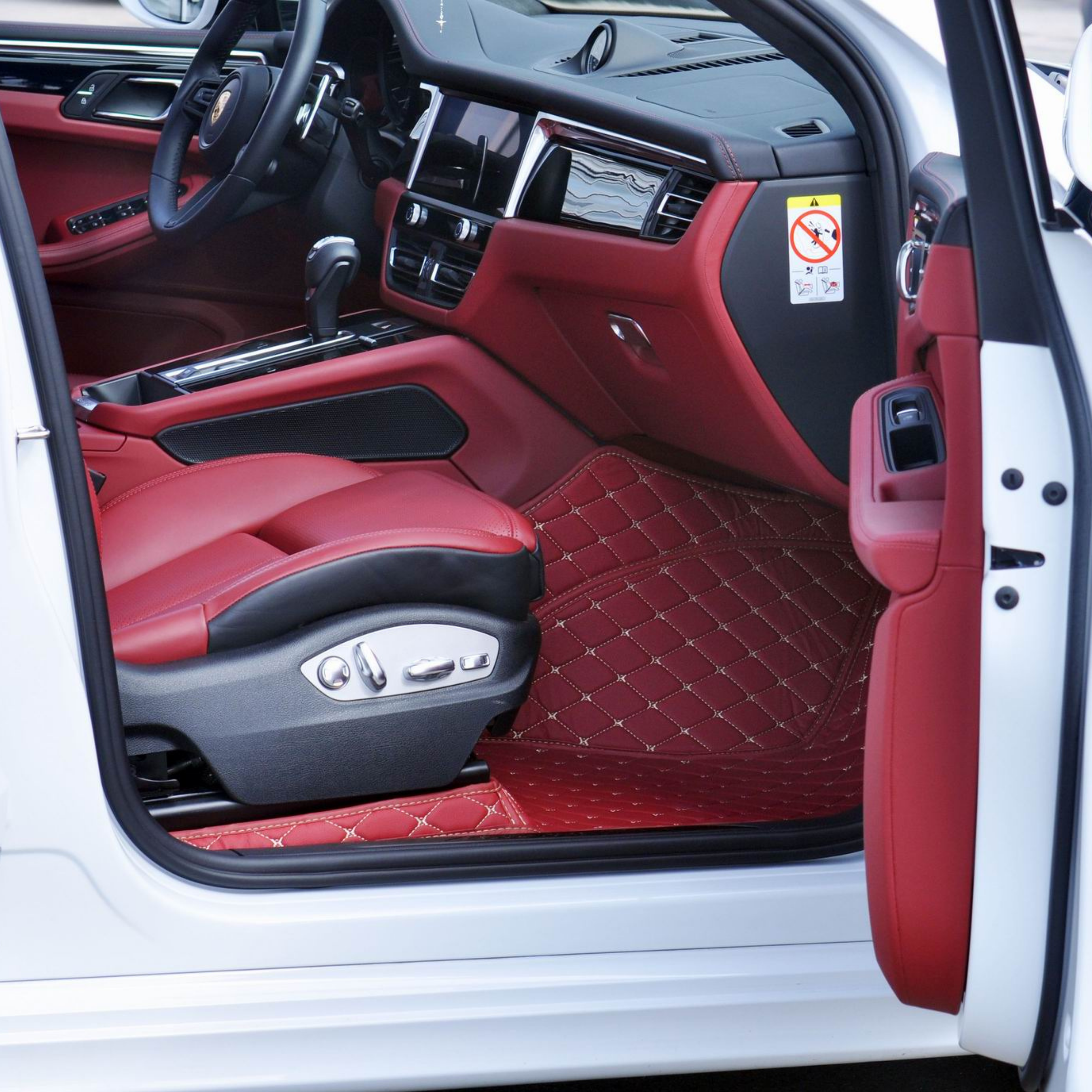 Car interior with red leather seats and dashboard, open driver's door.