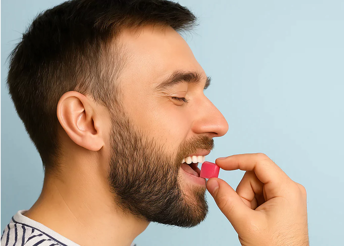 Man holding a pink cube near his mouth, smiling.