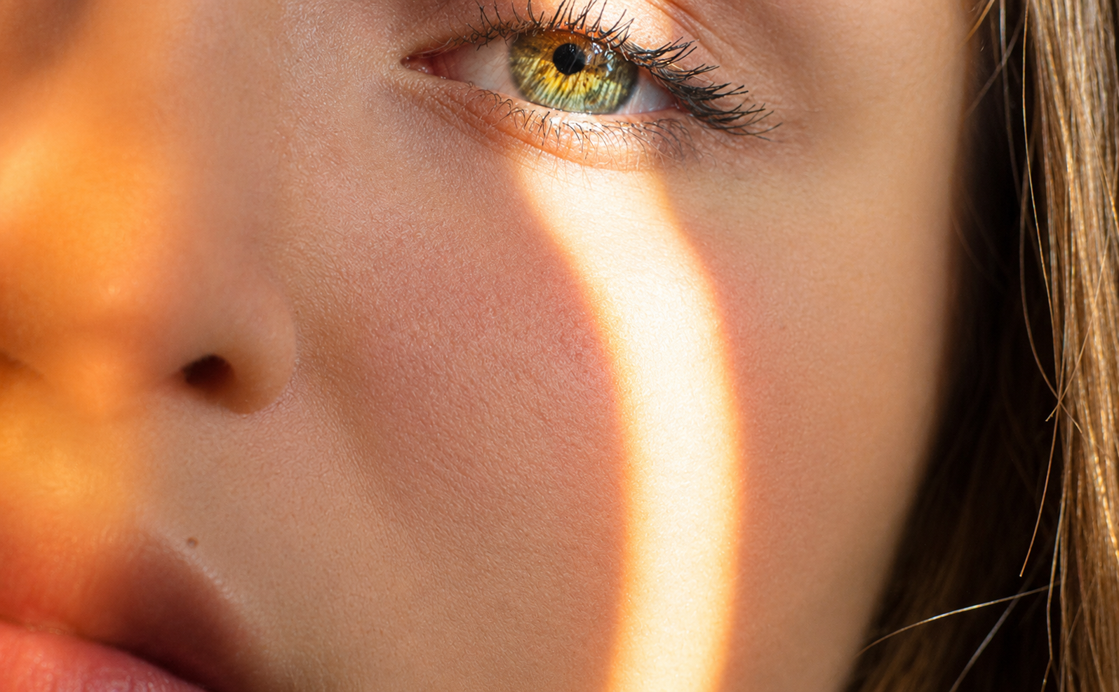 A close-up of a person's face, with a vertical band of sunlight shining across their hazel eye.