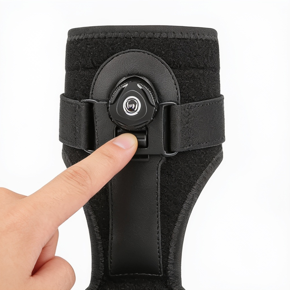 A finger presses a button on the dial of a black support brace against a white background.