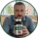 A man holds up a bottle of supplements towards the camera inside a circular frame.
