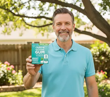 Man in blue shirt holding nicotine gum box outdoors.
