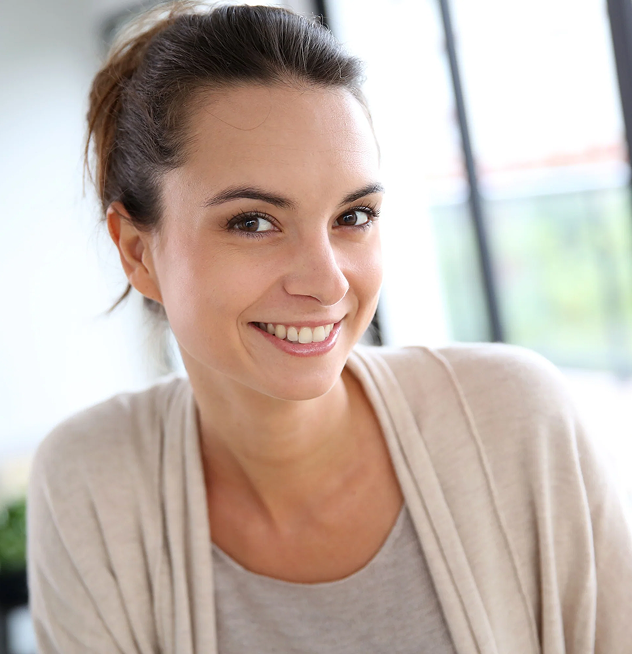 Smiling woman with brown hair in a light sweater, indoors.
