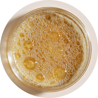Top view of a glass with bubbly amber liquid.