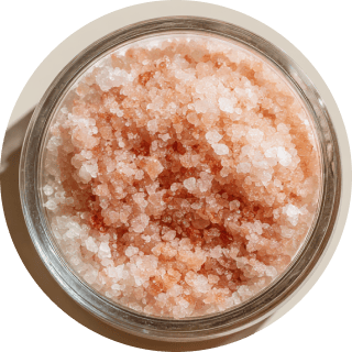 A glass jar filled with pink Himalayan salt crystals.