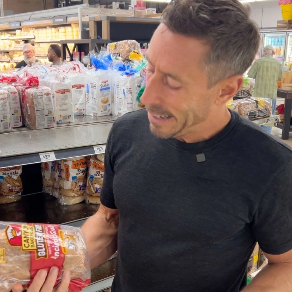 Person holding a package of gluten-free bread in a grocery store aisle.