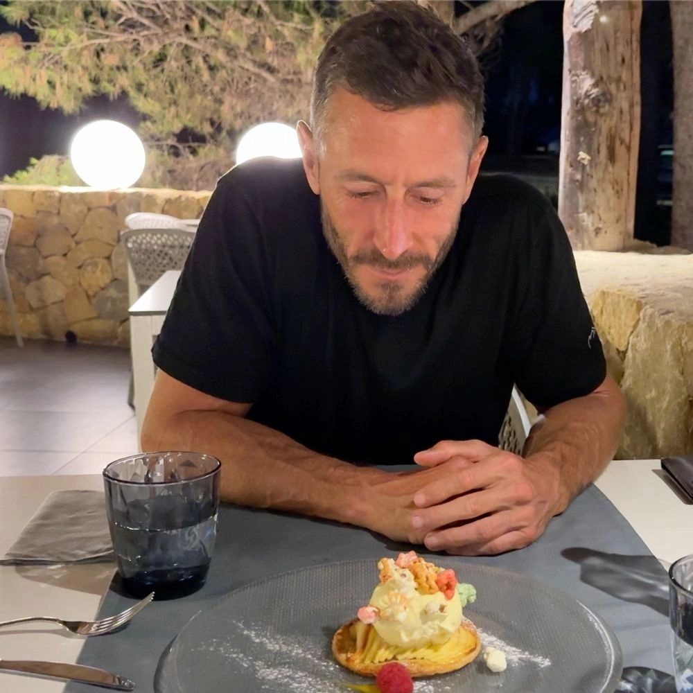 Person in black shirt looking at dessert on a table outside.