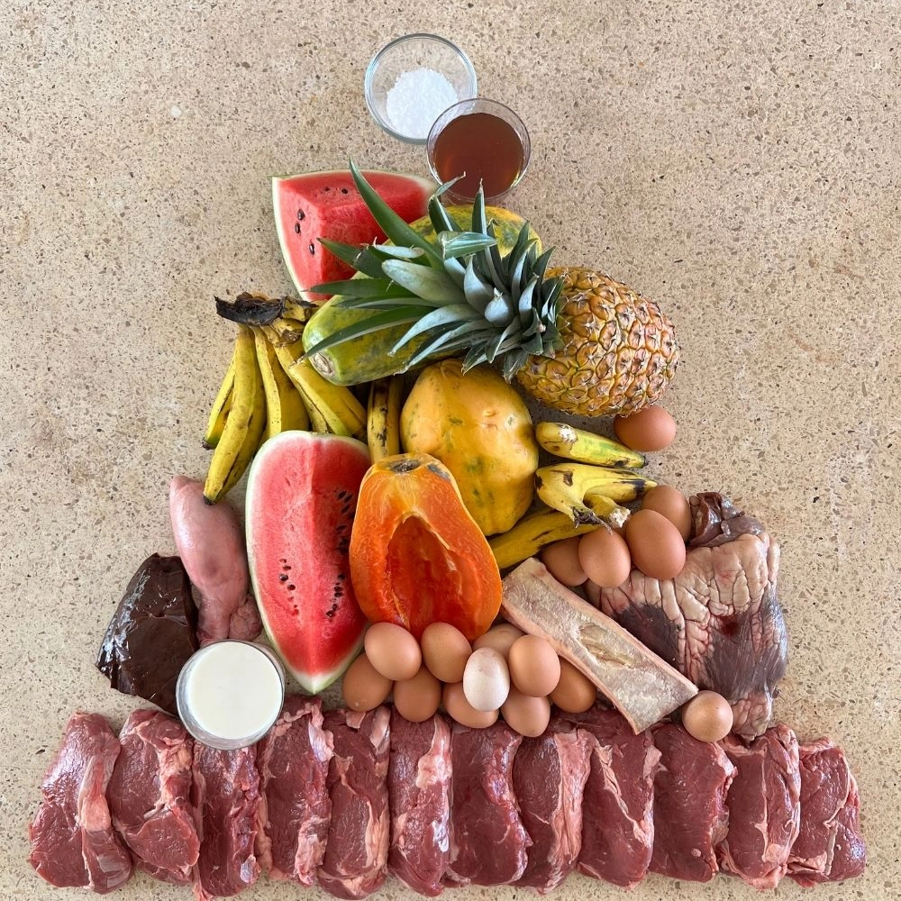 Assorted fruits, meats, eggs, and condiments arranged on a beige surface.