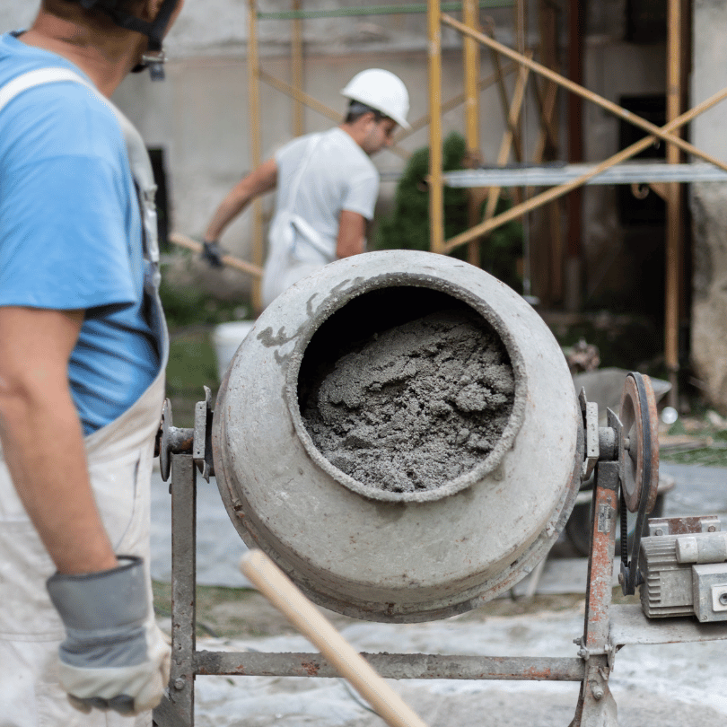Construction workers with a cement mixer on a building site.