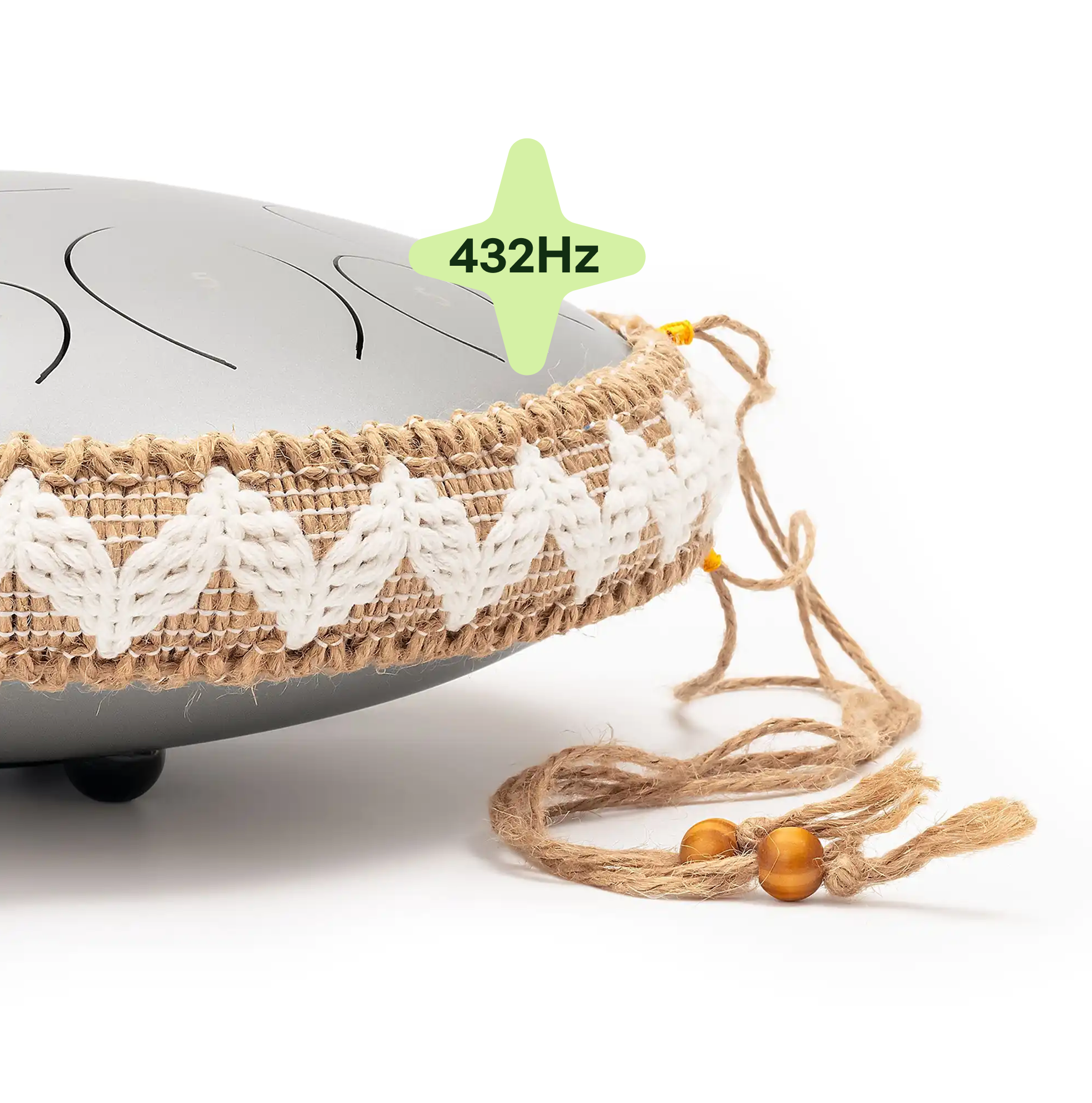A close-up of a grey steel tongue drum with a decorative woven jute and yarn band around it.