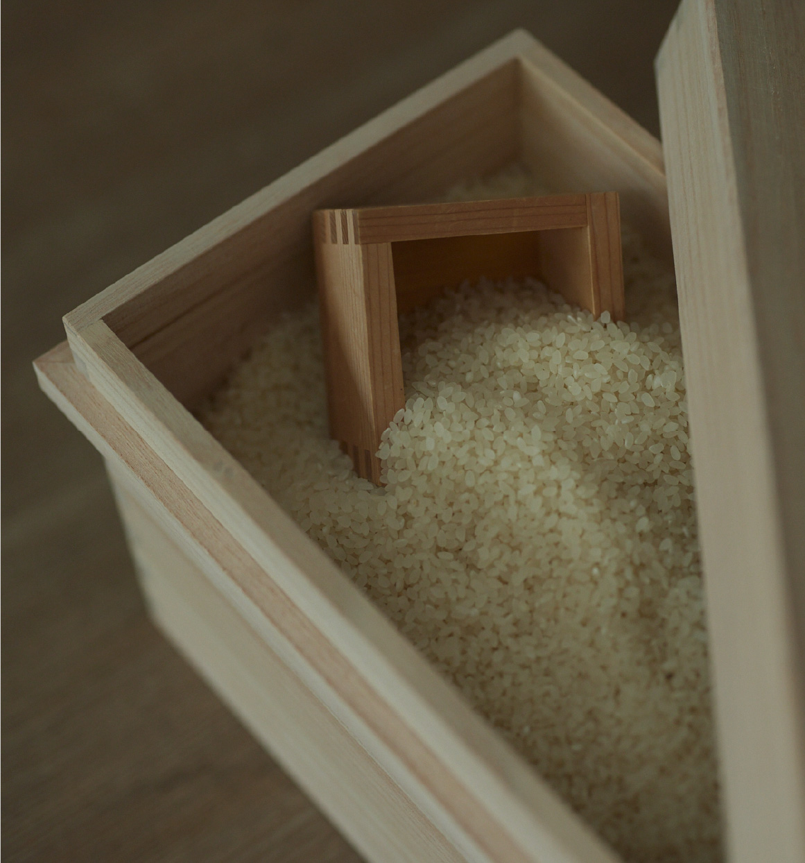 Wooden box filled with white rice and a small wooden scoop.