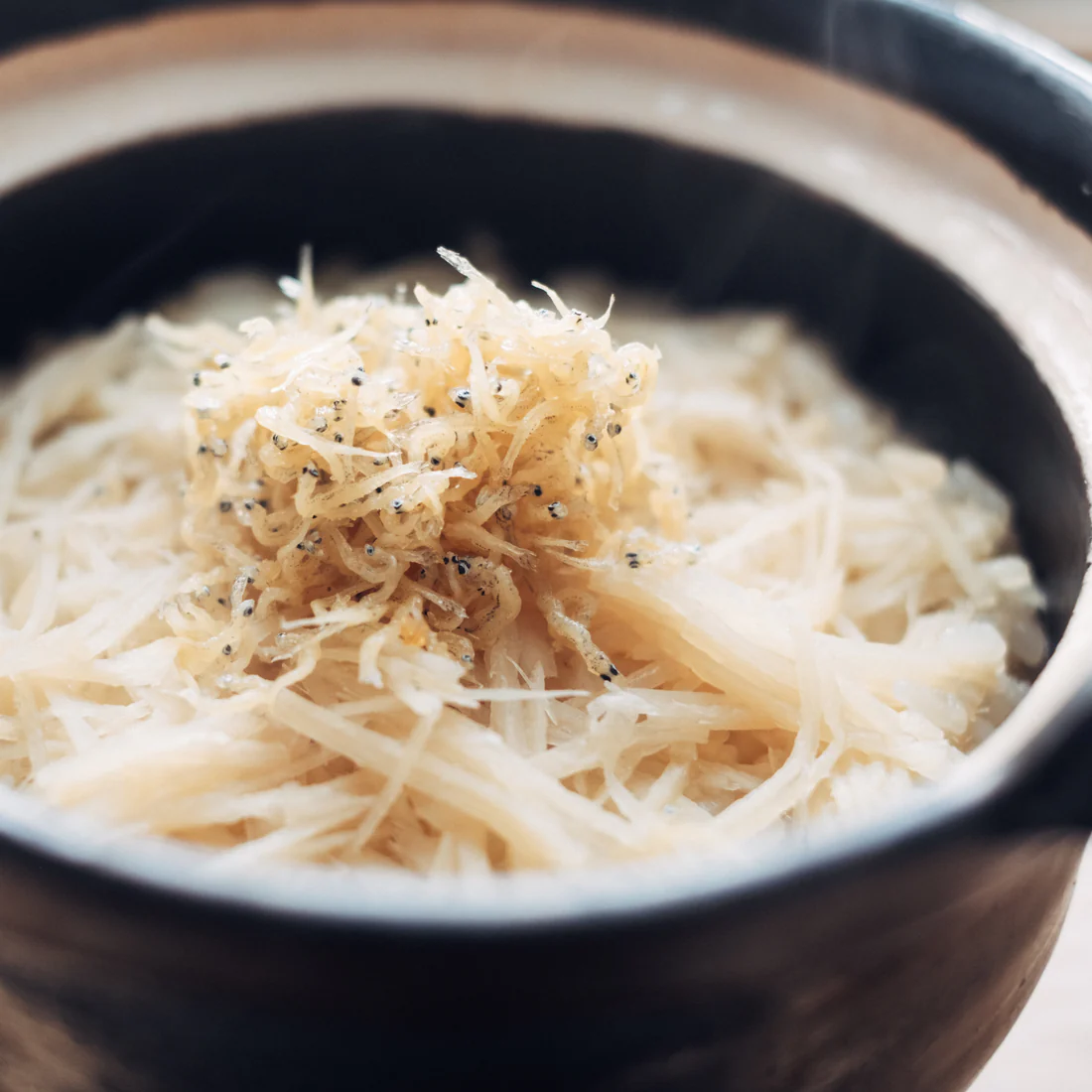 Close-up of grated food garnished with tiny fish in a bowl.