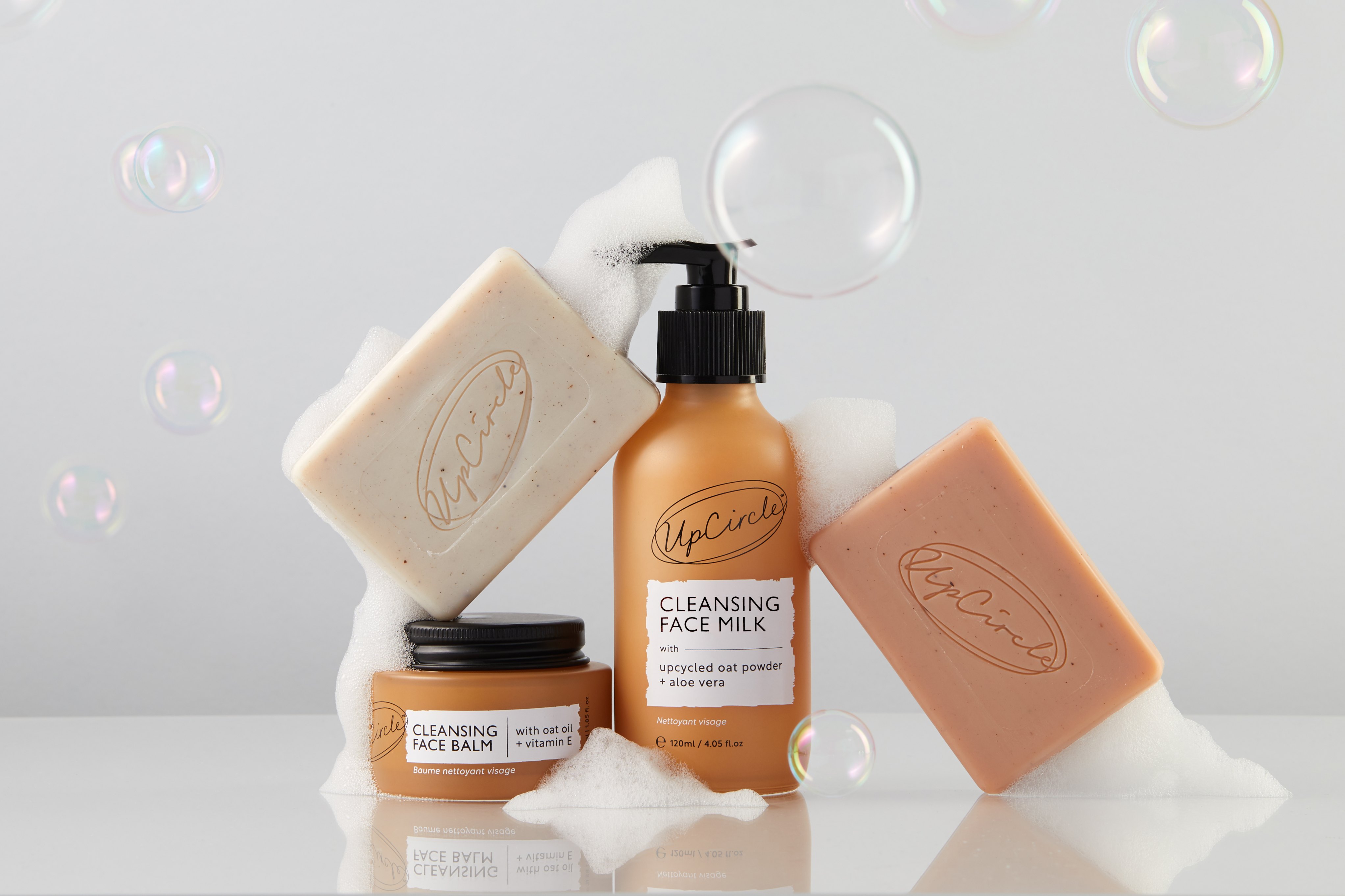 Skincare products with soap bars, cleansing milk, and bubbles.