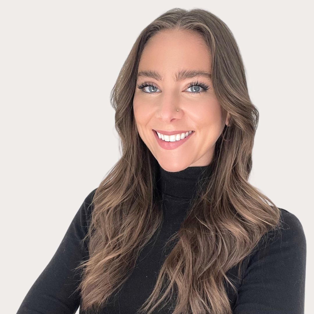 Smiling person with long brown hair wearing a black turtleneck.
