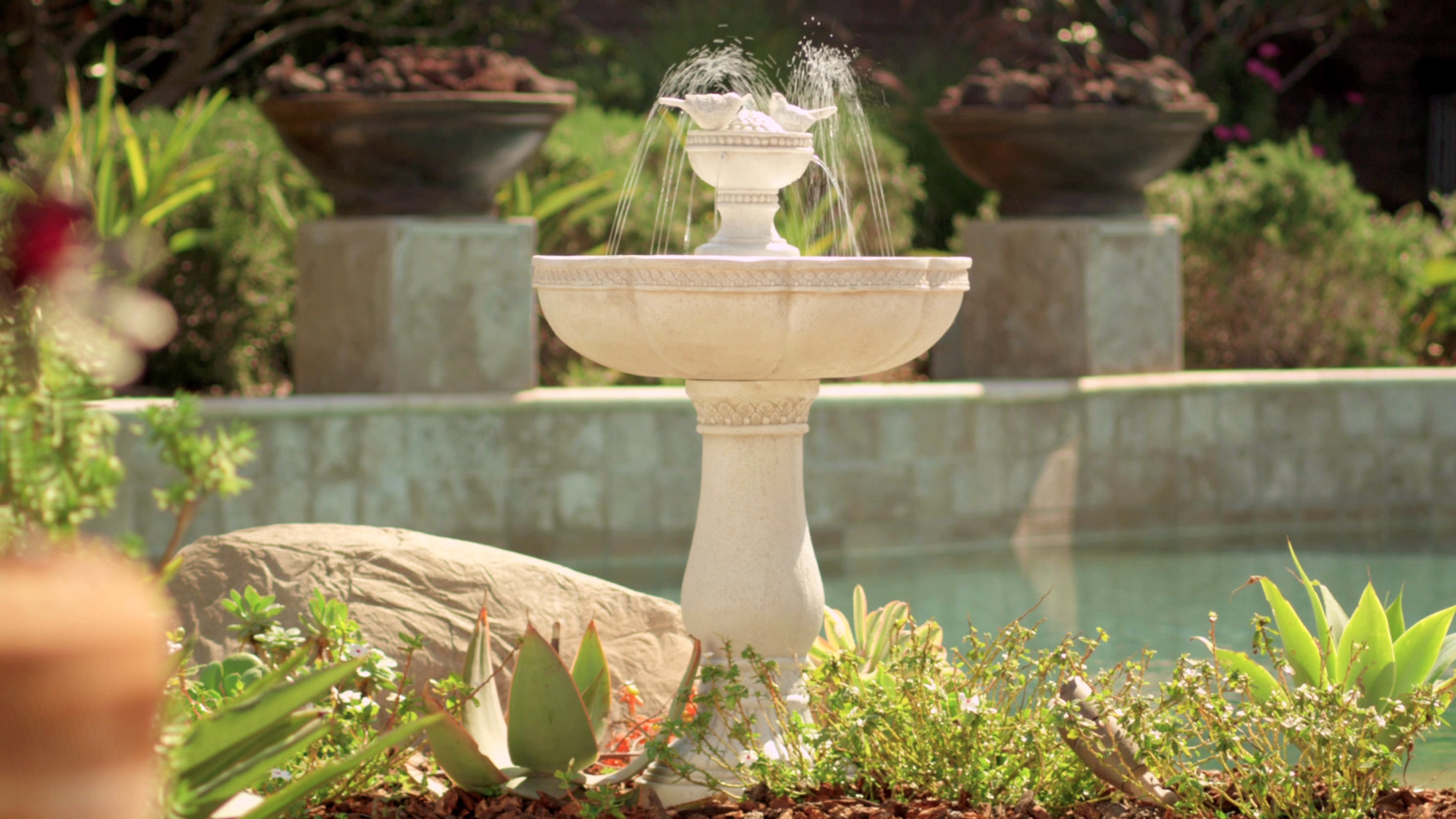 Stone fountain with water streams in a garden setting.