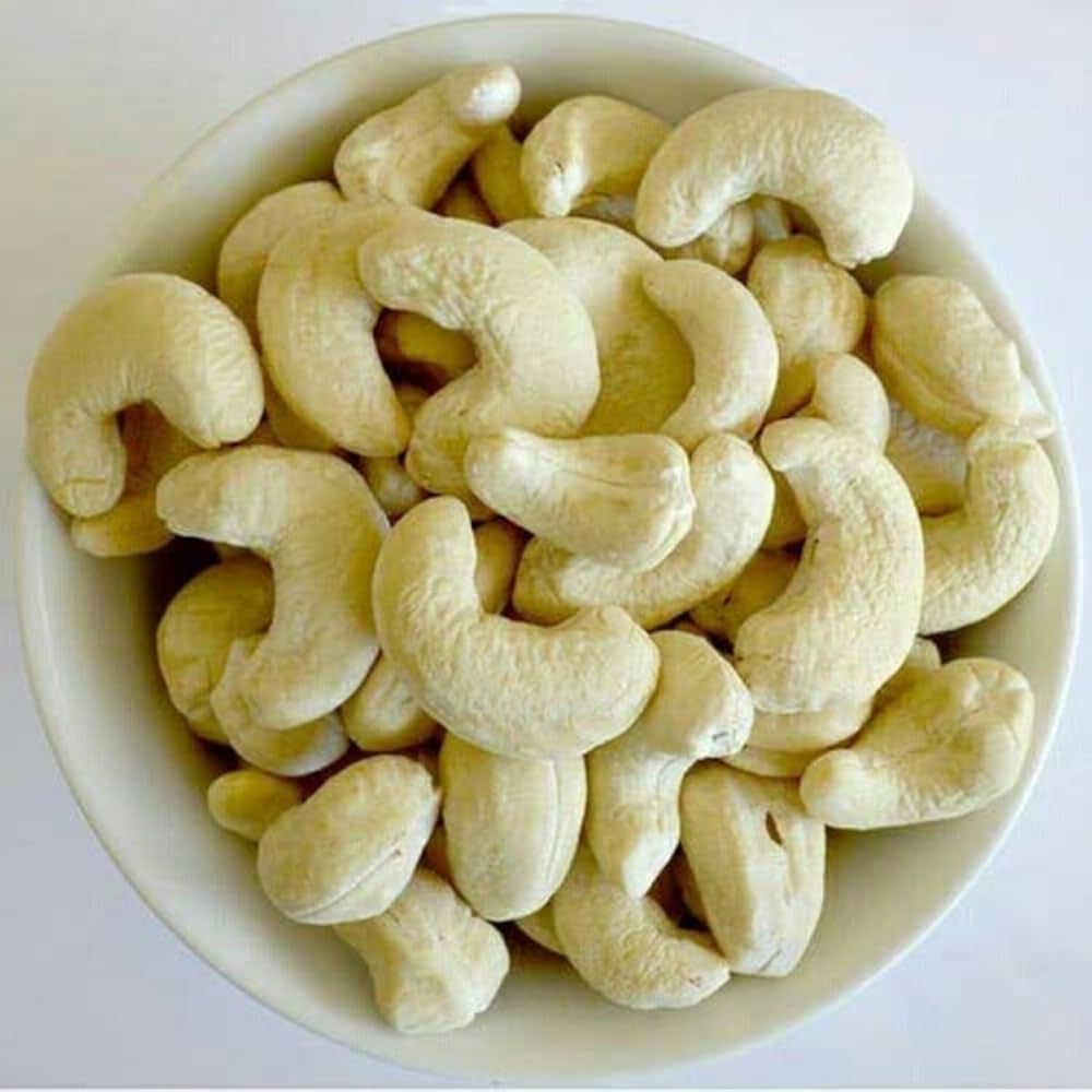 A bowl filled with raw cashew nuts on a white background.