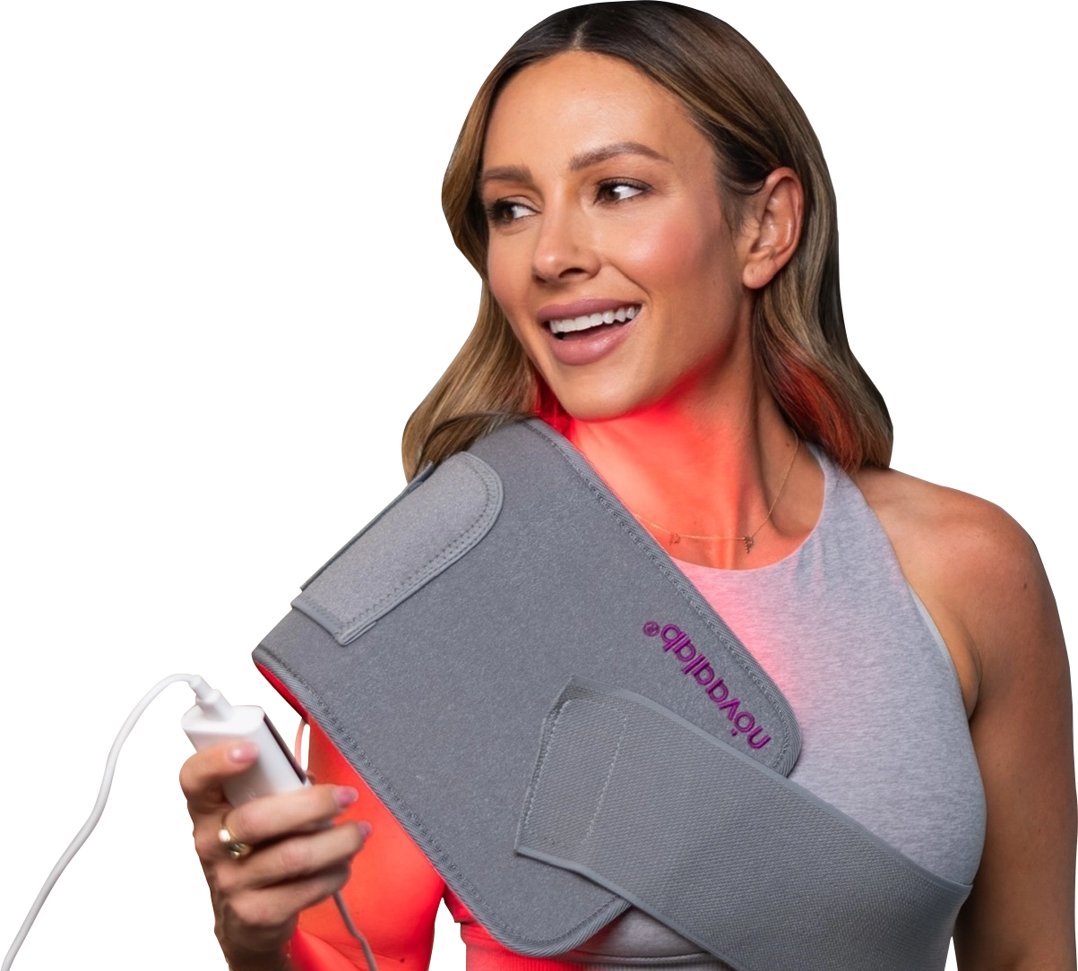 A smiling woman wears a glowing red light therapy device on her shoulder, holding the controller.