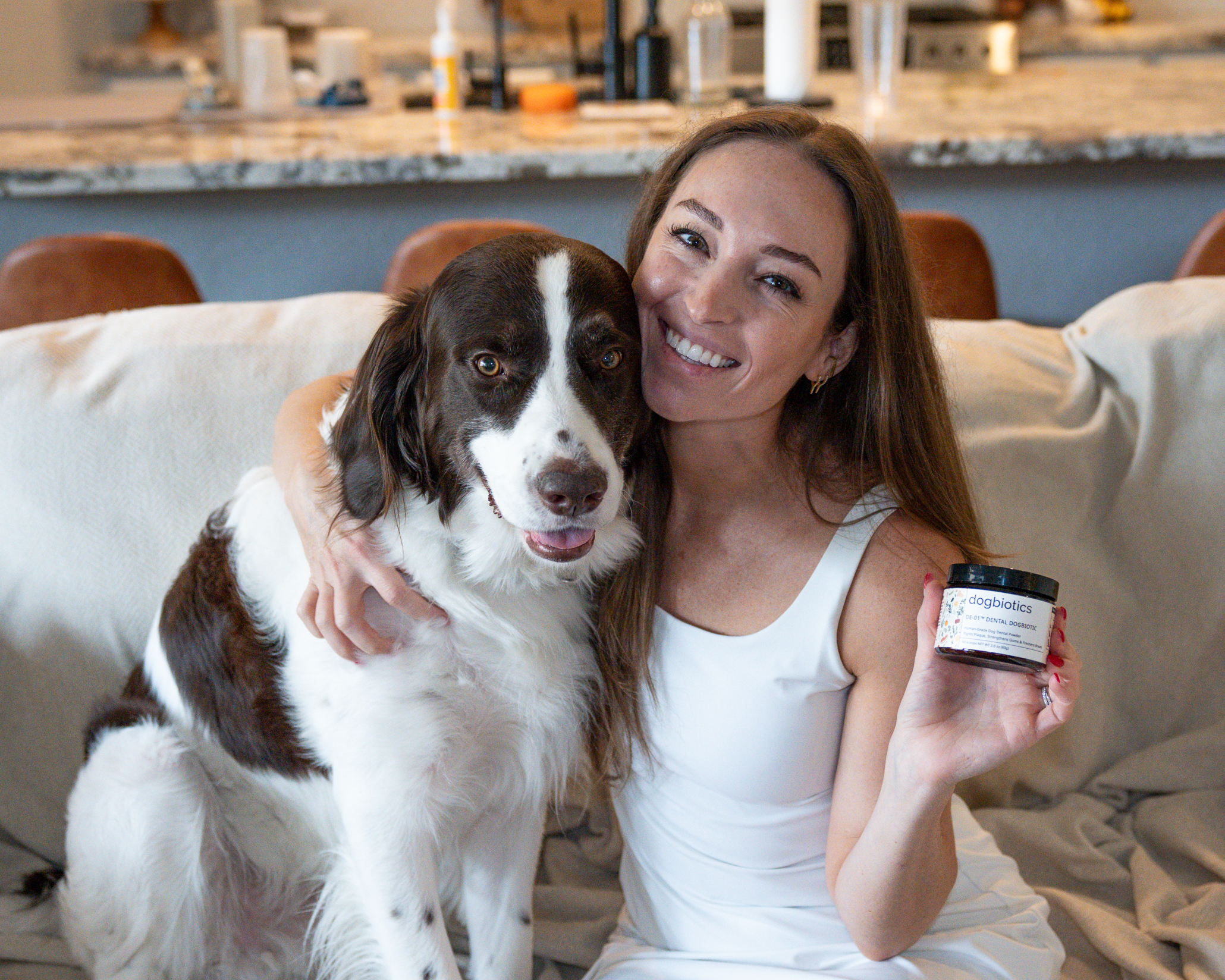 Woman hugging a dog while holding a container labeled 'dogbiotics.'