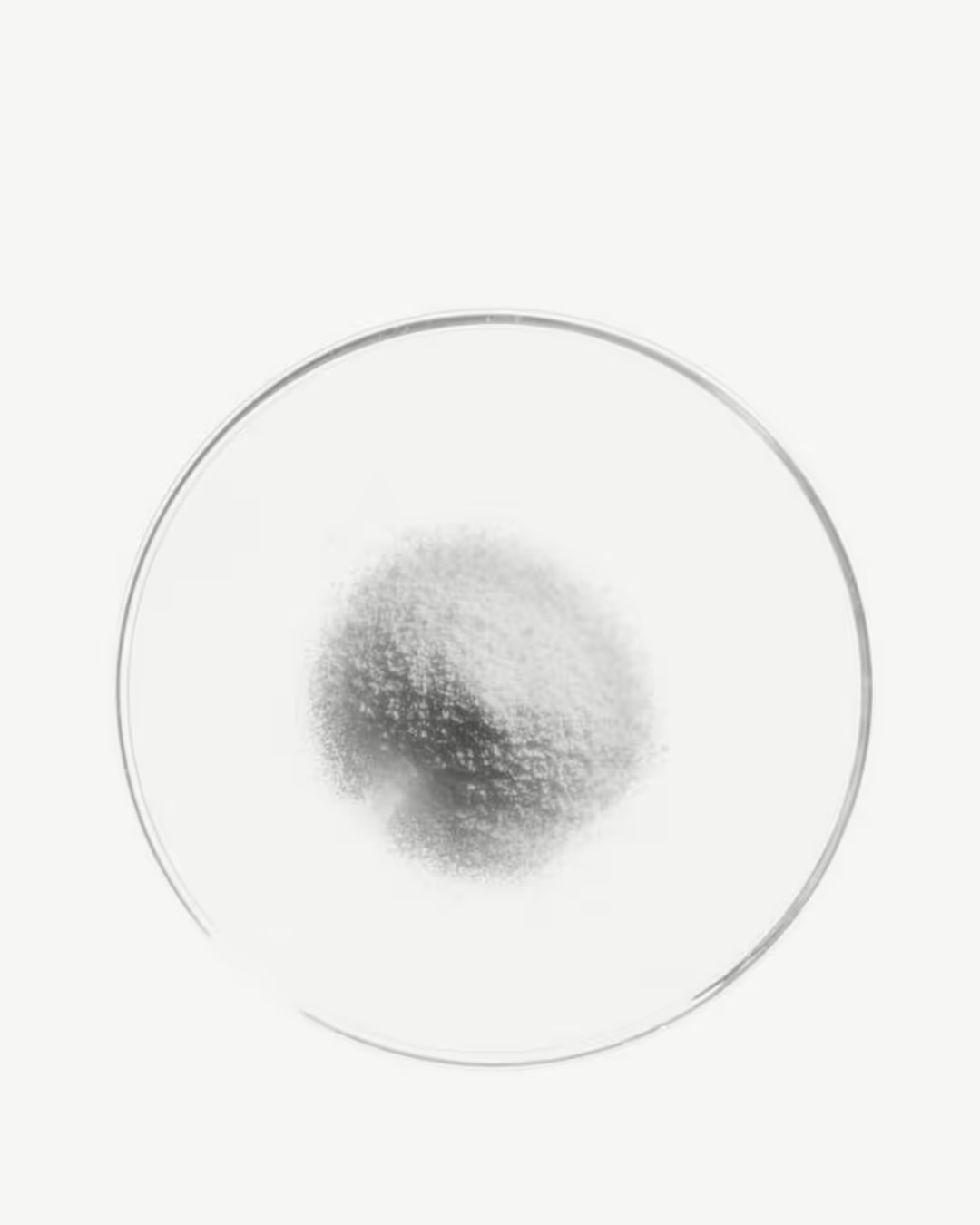 White powder in a clear glass dish on a white background.