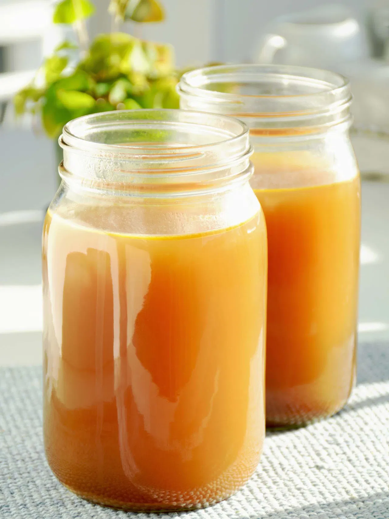 Two glass jars filled with orange liquid on a light-colored surface.