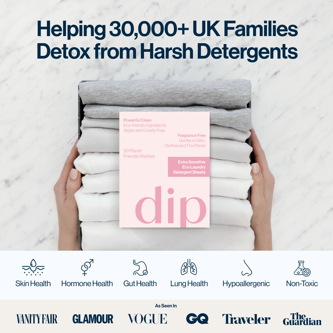 Hands holding folded clothes with a pink detergent sheet package on top.
