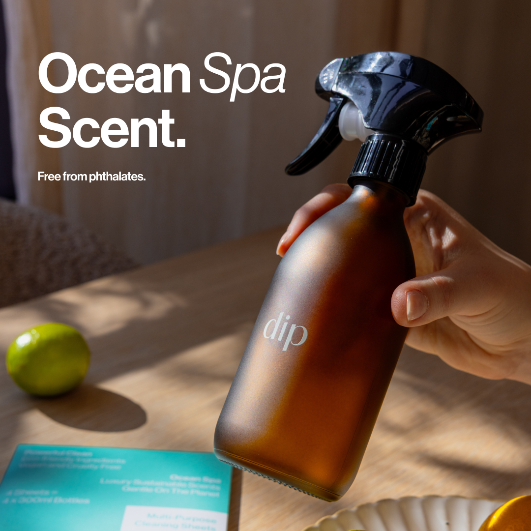 Hand holding a spray bottle labeled 'dip' on a table with text 'Ocean Spa Scent.'