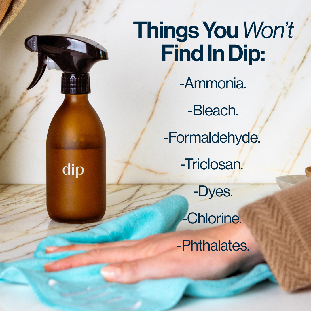 Spray bottle labeled 'dip' with list of chemicals not included, hand wiping surface.