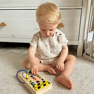 Toddler sitting on the floor playing with a wooden activity toy.