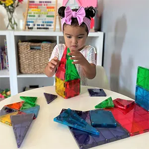 Child playing with colorful magnetic building blocks at a table.