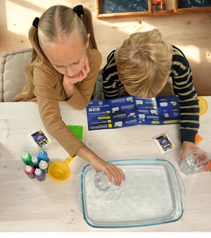 Two children conducting a science experiment with water and materials on a table.