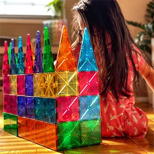 Child playing with colorful magnetic tiles on the floor.