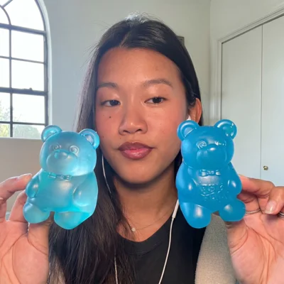 A woman holds up two large, translucent blue, bear-shaped objects.