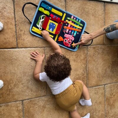Child on floor reaching for toy activity board.