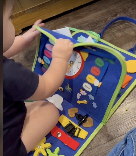 Child playing with a colorful educational activity book on the floor.