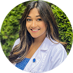 Person in a white coat against a plain background.