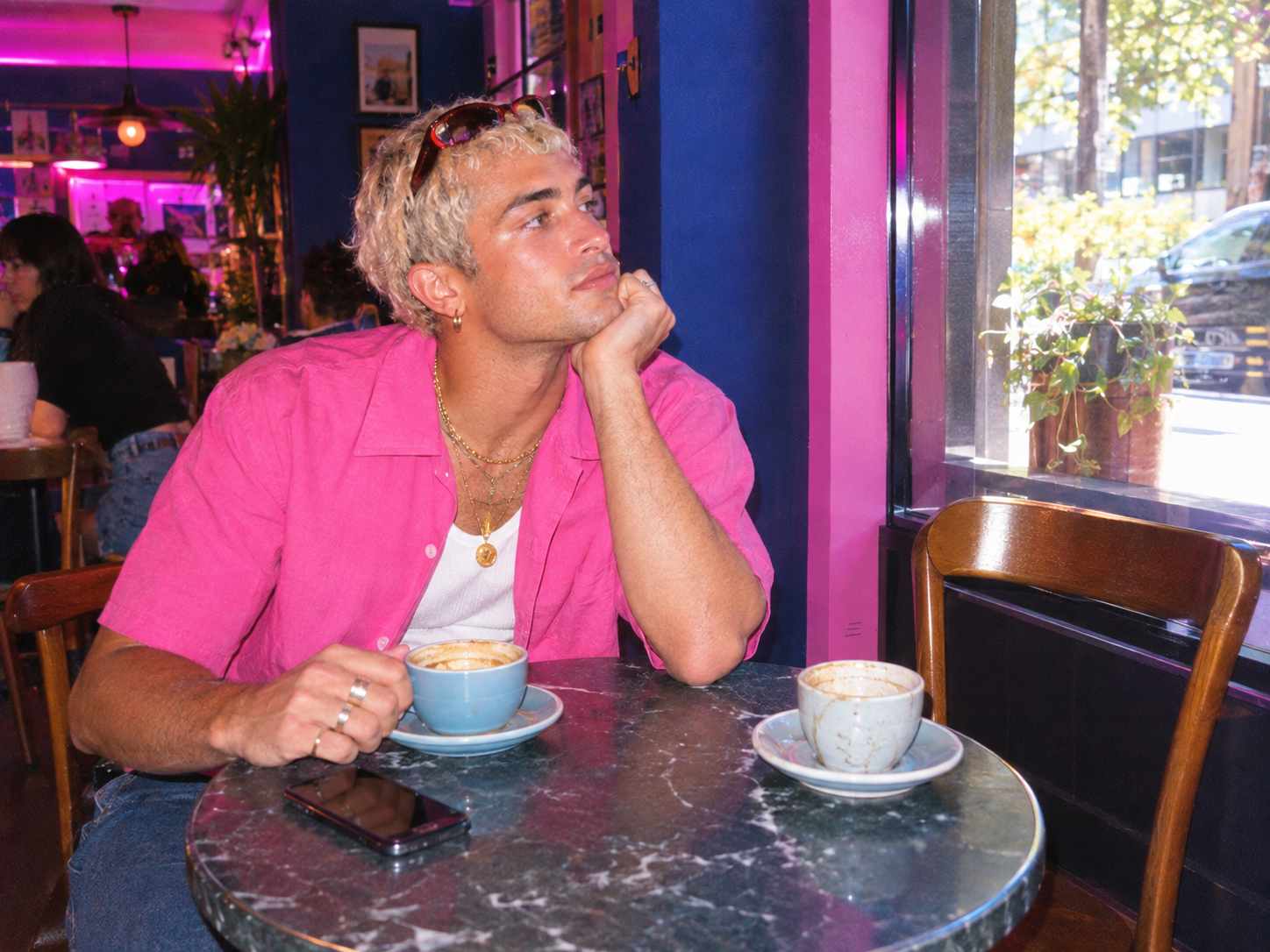 A man waiting alone at a cafe table with an empty chair opposite him
