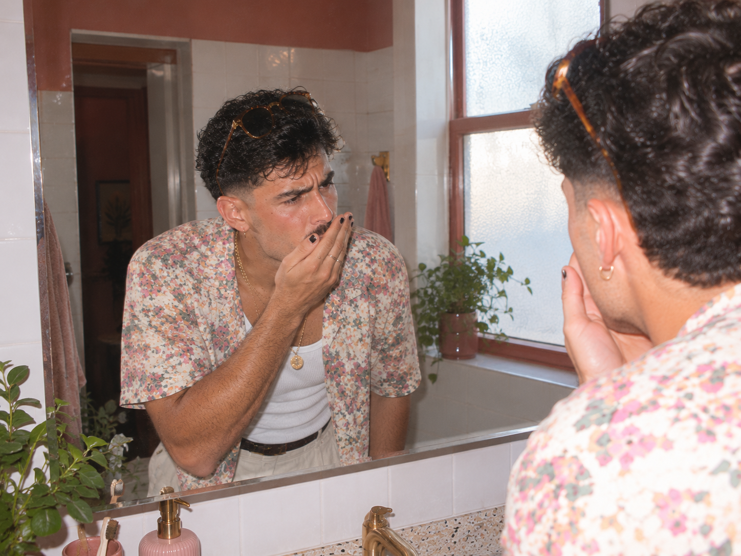 A man checking his own breath in a cafe bathroom mirror