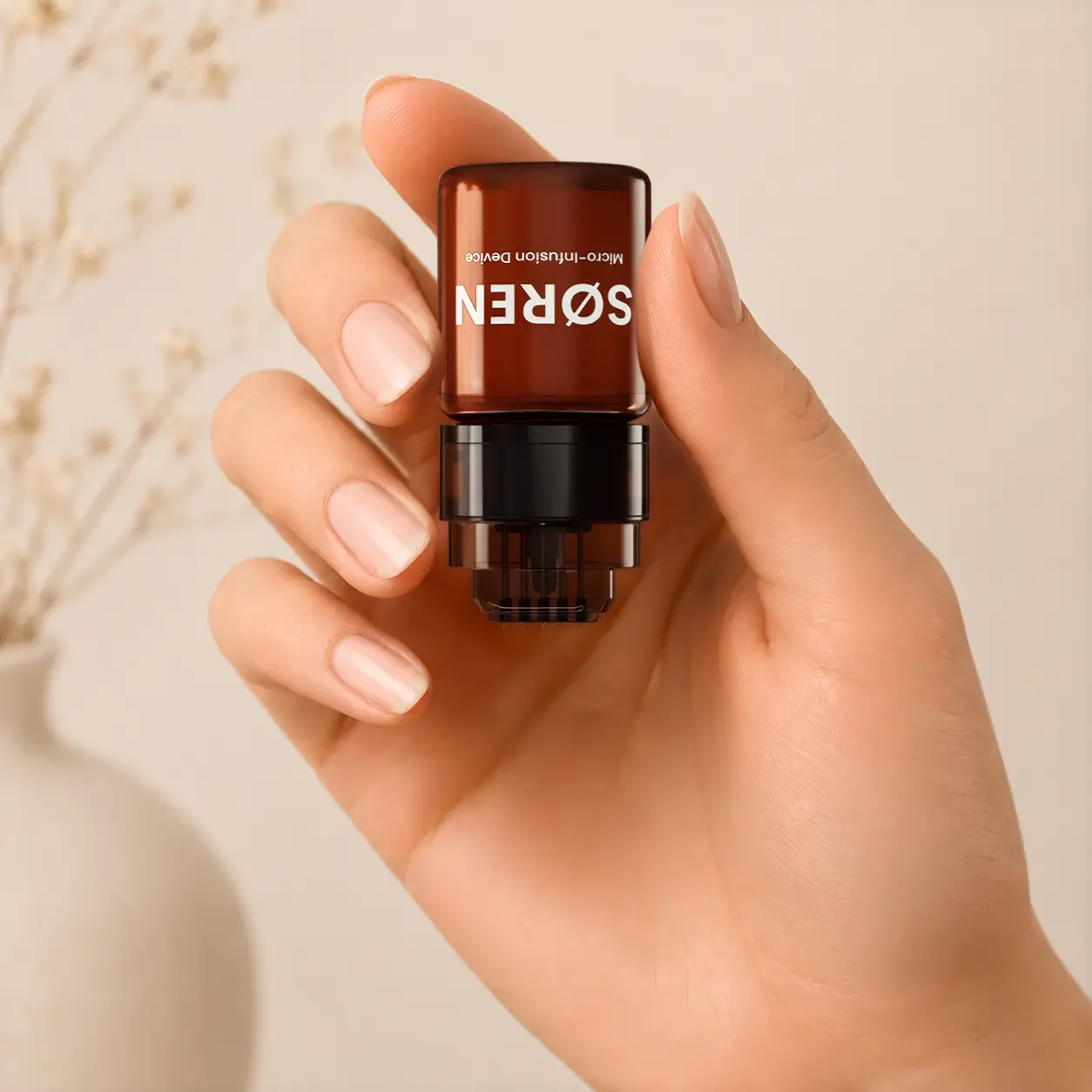 Hand holding the assembled SØREN micro-infusion device upside down.