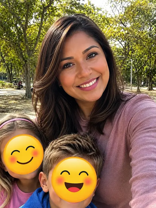 Woman smiling outdoors with two children.