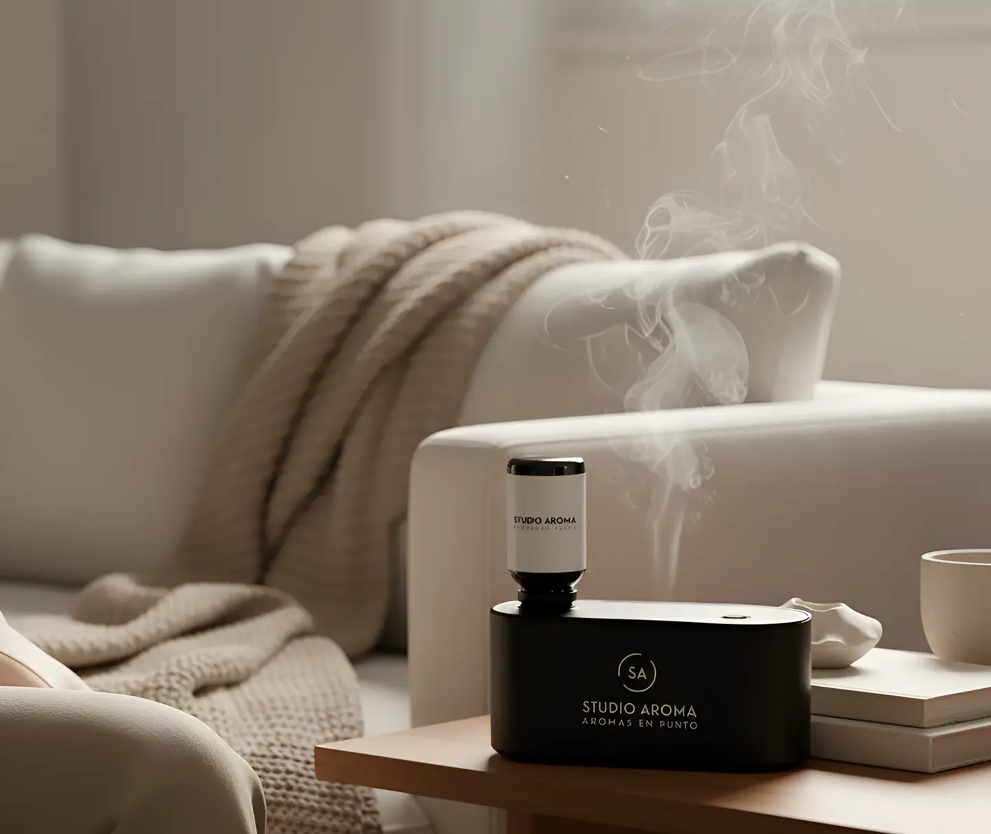 Aromatherapy diffuser emitting vapor, with books and a cup on a table near a sofa.