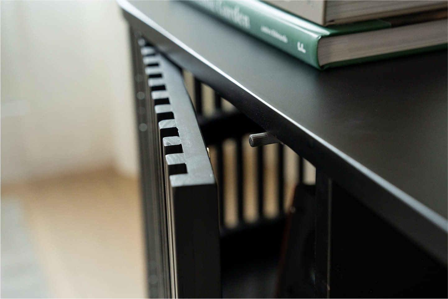 Close-up detail of furniture drawer with fluted wood face and black metal handle.